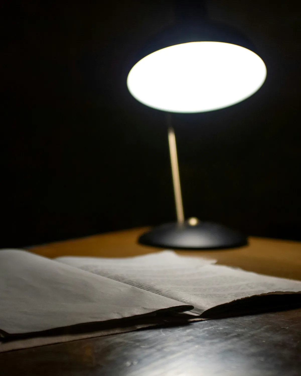 Une lampe de bureau allumée au-dessus d’un dossier ouvert