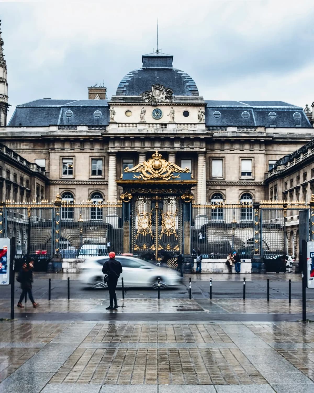 La grille dorée et la façade du Palais de Justice de Paris, parvis mouillé