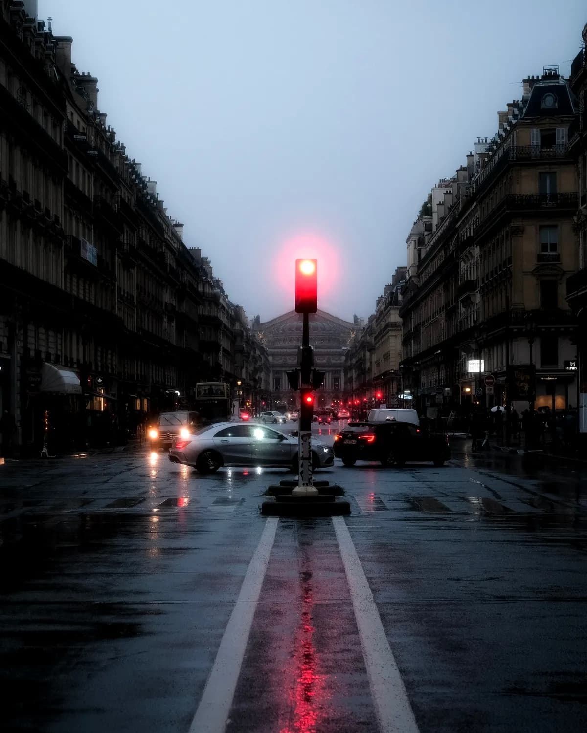 Une avenue parisienne sous la pluie à la tombée de la nuit